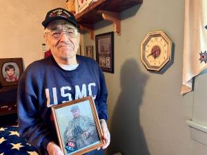 Michael S. Lockett / The Daily World
Jim Evans, one of the Chosin Few, poses in his residence with a picture of Marine Corps legend Chesty Puller.