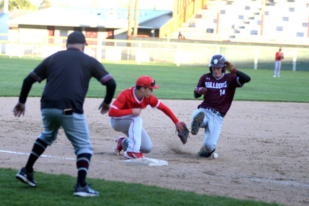 RYAN SPARKS / THE DAILY WORLD 
Montesanos Kaleb Ames (14) slides in safe against Castle Rock third baseman Trevor Rogen in the Bulldogs 7-4 1A District 4 Tournament win on Monday in Hoquiam.