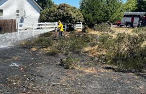 Michael S. Lockett / The Daily World
Firefighter/EMT Nick Frymire of the Ocean Shores Fire Department sprays down a burned area caused by a grass fire on July 18.