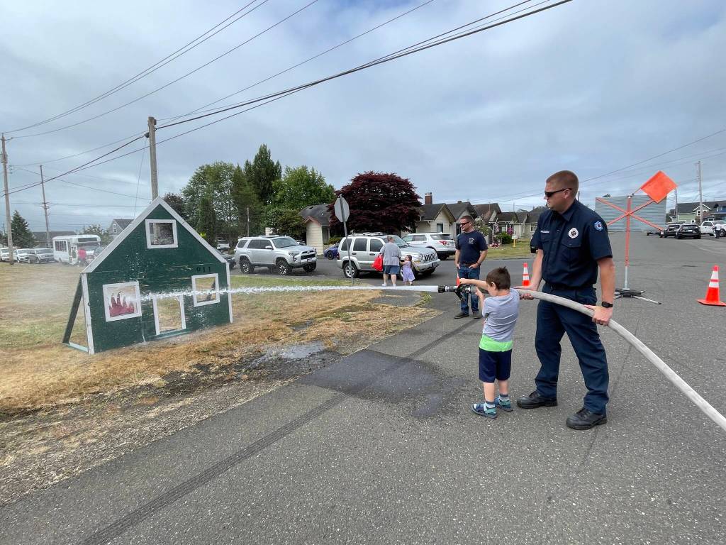 Aberdeen fire services specialist Mitch Housden helps a guest at the countys Emergency Preparedness Expo get his hose on target on July 22. (Michael S. Lockett / The Daily World)