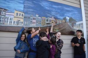 Matthew N. Wells / The Daily World
A small group who helped create a diptych  merging two panels into one seamless one  point to portions of their artistic contributions. From left, Maddie and Abbi Cihak, Gabby Schreck, Ellie Cihak, Chloe Long and Jackson Cihak, were all smiles Tuesday evening after the hanging of the two panels. The panels show prominent buildings from parts of Cosmopolis early history.