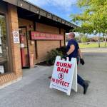Hoquiam fire Capt. Brandon Ray carries in a burn ban sign as the county eases restrictions with the advent of cooler, damper fall weather on September 19. (Michael S. Lockett / The Daily World)