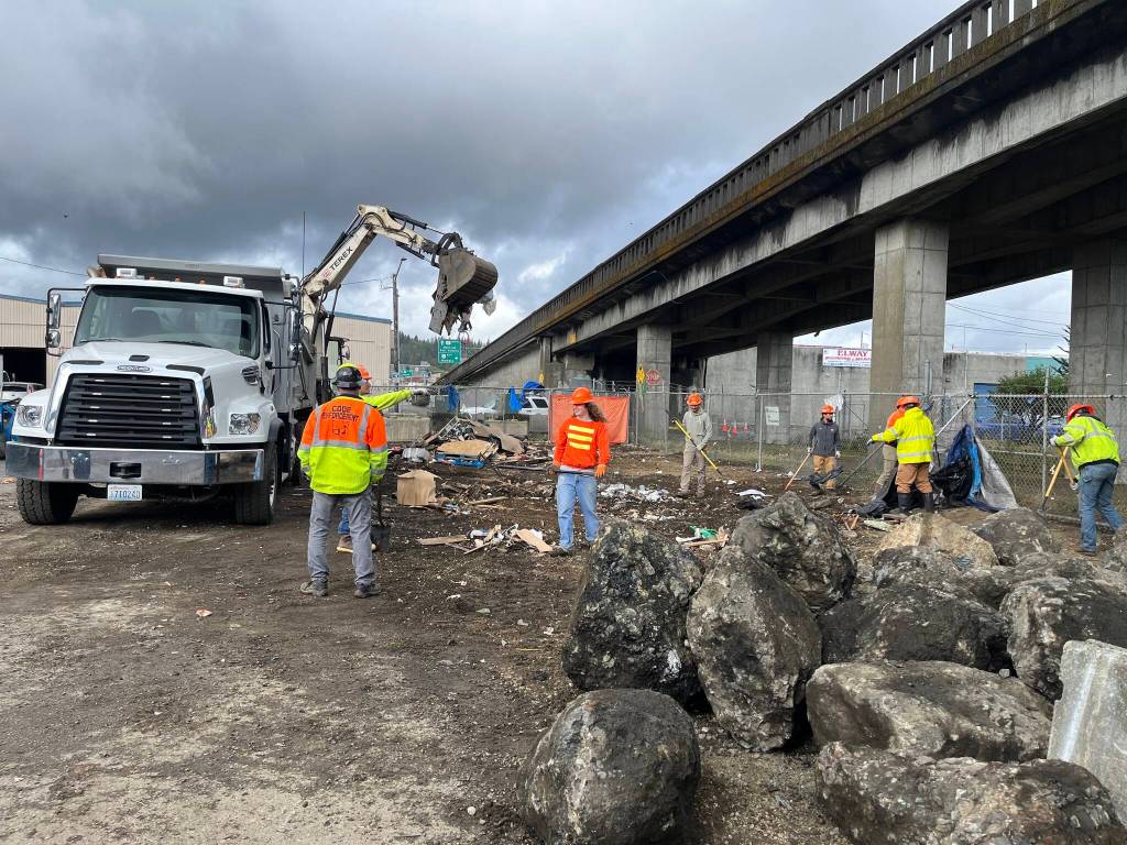 Matthew N. Wells / The Daily World
A city of Aberdeen Code Enforcement staffer watches a construction vehicle scoop up remnants of unhoused peoples self-constructed homes from the State Street encampment underneath the Chehalis River Bridge. The area is being cleaned up for health and safety reasons. The homeless people who live at the encampment were moved temporarily Wednesday and theyll be allowed to move back.