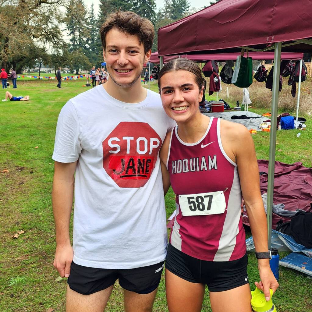 RYAN SPARKS | THE DAILY WORLD Hoquiam standout Jane Roloff, right, stands with former teammate and current Saint Martins University runner Timmy Higgins, who adorned a Stop Jane T-shirt at the 1A Evergreen Championship cross-country meet on Thursday at the Oaksridge Golf Course in Elma.
