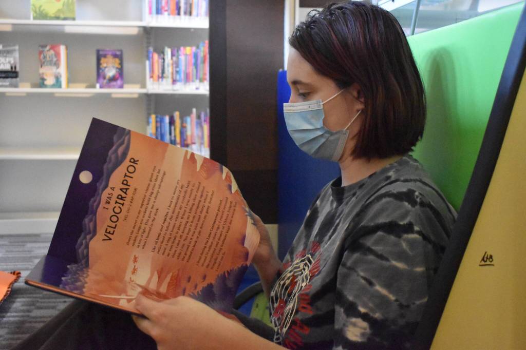 Naomi Watkins, a 21-year-old Hoquiam resident, has visited the library nearly every day for the past 10 years. She found her secondary home, when she was in fifth grade. Now, Watkins loves reading to her niece. Her niece loves dinosaurs, so it tickled Watkins to see Book of Dinosaurs  10 Record Breaking Prehistoric Animals. (Matthew N. Wells / The Daily World)