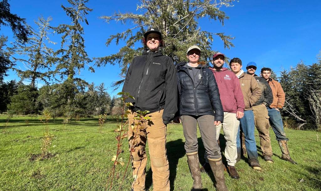 Grays Harbor Conservation Districts work crew poses behind a tree they recently planted, one of thousands, as part of a riverbank repair effort. (Michael S. Lockett / The Daily World)