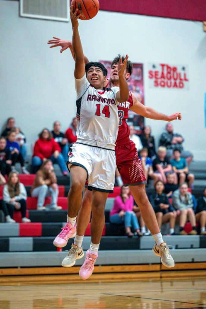 PHOTO BY FOREST WORGUM Raymonds Chris Quintana (14) scores while Hoquiams Aiden Butcher defends during the Grizzlies 68-41 win on Friday at the Raymond New Years Classic in Raymond.