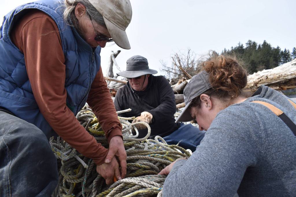 Clayton Franke / The Daily World
From left: Julie Puhich, Bruce Rittenhouse and Nicole Baker use knives to dissect a large tangle of rope. As it was found, the rope was too large and heavy to be hauled away from the beach.