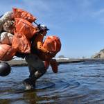 Kyle Deerkop, farm operations manager with Pacific Shellfish, crosses a creek hauling pounds of marine debris collected from a beach on the Quinault Indian Reservation. (Clayton Franke / The Daily World)