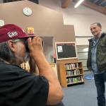 Clayton Franke / The Daily World
Ken Stevens, a Quinault tribal elder and former Taholah School Board member, peers into a virtual reality headset at the Taholah School Library on April 6 as Bill Adams, current school board member, looks on. As part of an open house to get ideas for the new planned Taholah school, the headset gave Stevens a virtual tour of the recently-constructed Toledo High School, which was designed by the same firm the district hired in Taholah.