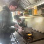 Matthew N. Wells / The Daily World
James Covault, grill cook, seemed to be in good spirits when he gave a brief soundbite as to how it is at Clarks Restaurant. Its a real community here, Covault said after he finished cooking this homemade bacon cheeseburger.