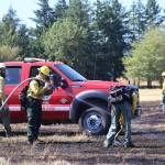 DNR wildland firefighters extinguish hotspots with water and hand tools from a grass fire near Elma on Saturday. (Michael S. Lockett / The Daily World)