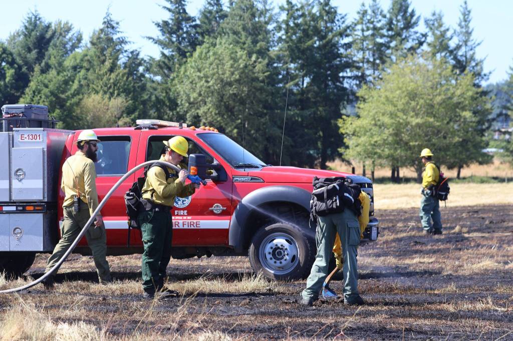 DNR wildland firefighters extinguish hotspots with water and hand tools from a grass fire near Elma on Saturday. (Michael S. Lockett / The Daily World)