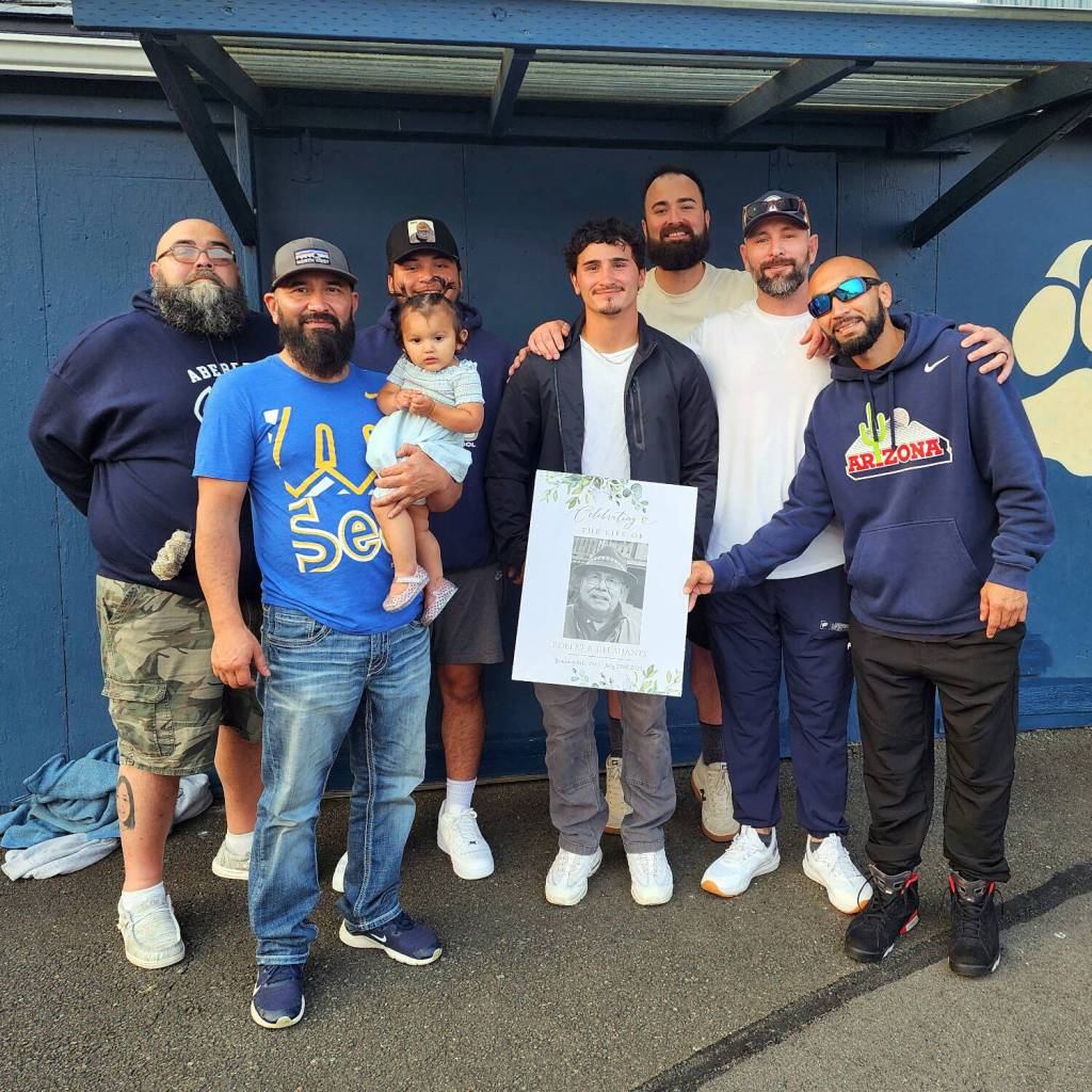 RYAN SPARKS | THE DAILY WORLD Family members of veteran Aberdeen crew chief organizer Bob Delahanty pose with a photo of Bob ahead of Aberdeens game against Olympic on Friday at Stewart Field in Aberdeen.
