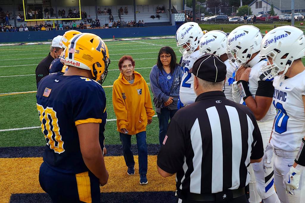 RYAN SPARKS | THE DAILY WORLD Catalina Delahanty (middle), widow of beloved Aberdeen chain crew organizer Bob Delahanty, participates in the coin toss ahead of Aberdeens game against Olympic on Friday at Stewart Field in Aberdeen.