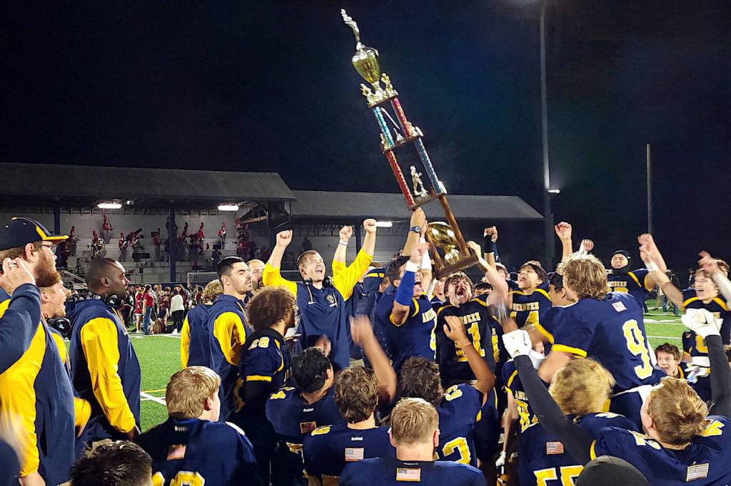 RYAN SPARKS | THE DAILY WORLD Aberdeen assistant coach David Tarrence (arms raised) watches Adonis Hammonds (4) and Riley Wixson (11) raise the Myrtle Street Trophy after beating Hoquiam 34-9 on Friday at Stewart Field in Aberdeen.