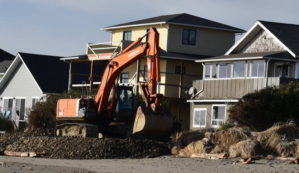 A backhoe operator lays cobble for the new south shore berm in front of private residences along Marine View Drive Southeast in Ocean Shores.