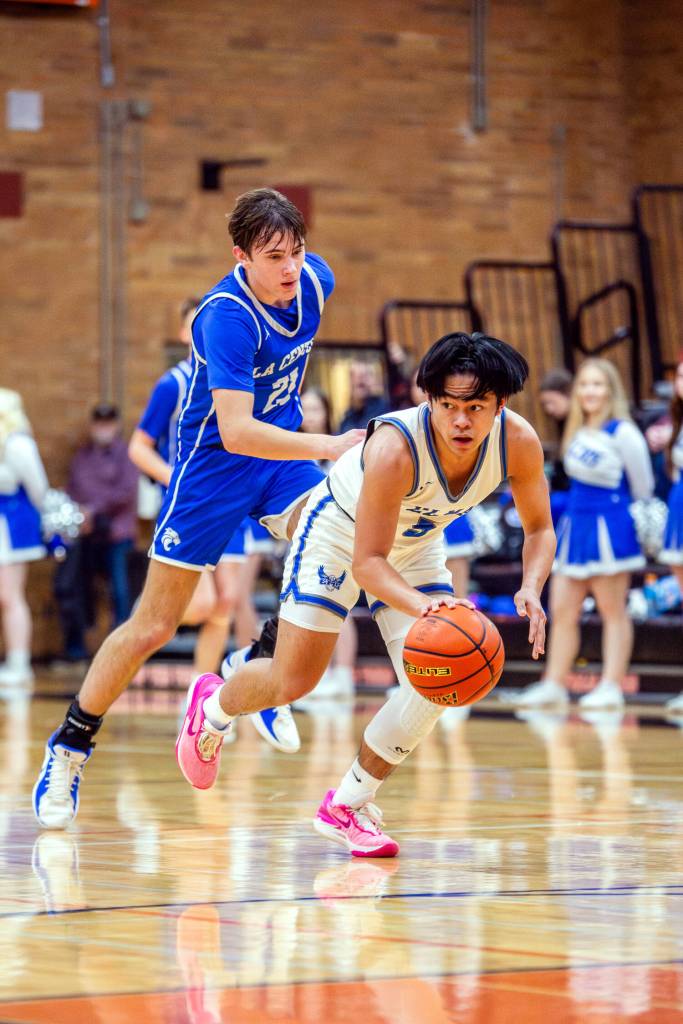 PHOTO BY MIKE ROBERTS Elmas Theo Flores (right) picks up a loose ball during the Eagles 62-47 loss to La Center in a 1A District 4 elimination game on Saturday in Centralia.