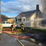 Firefighters pour on the water at two homes under fire.