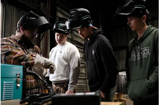 Skills & Drills workshop participants watch a stick welding demonstration.