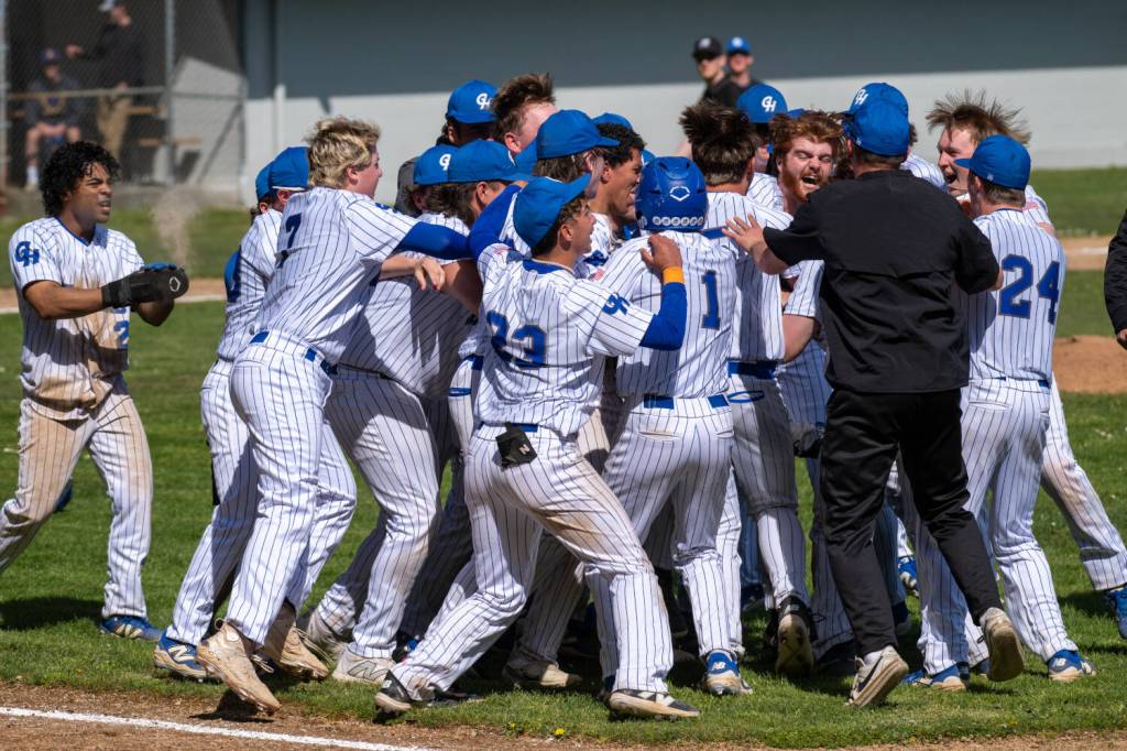 PHOTO BY FOREST WORGUM The Grays Harbor Chokers celebrate with Will Scharf (red beard) after he knocked in the tying and game-winning runs in a 6-5 win over Clark College on Sunday at Olympic Stadium in Hoquiam.