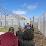 Personnel with the Department of Children, Youth and Families and the Department of Corrections walk on a fenced path between outdoor areas for Harbor Heights, left, and Stafford Creek Corrections Center, right, during a media tour on Thursday, May 29.