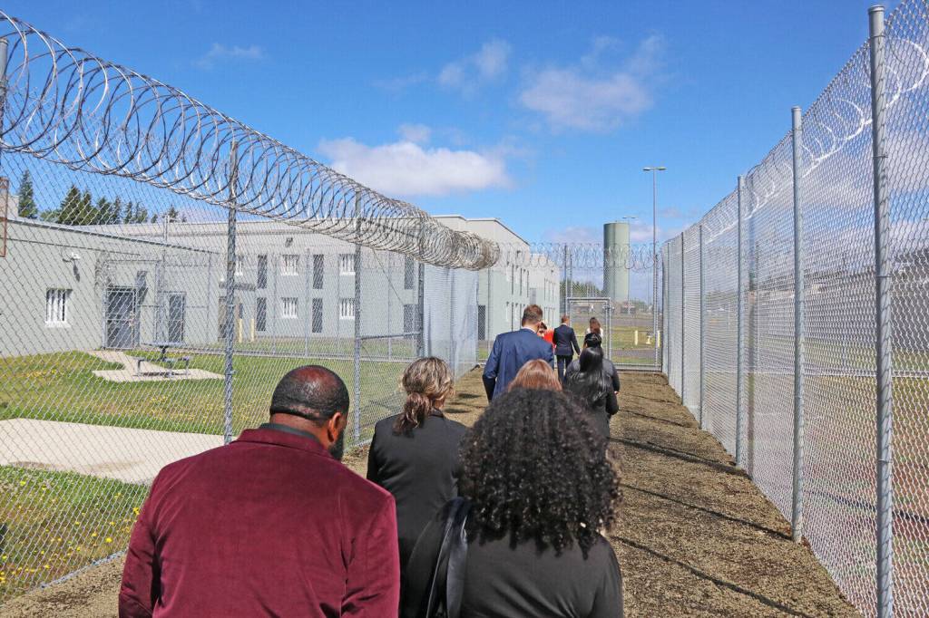 Personnel with the Department of Children, Youth and Families and the Department of Corrections walk on a fenced path between outdoor areas for Harbor Heights, left, and Stafford Creek Corrections Center, right, during a media tour on Thursday, May 29.
