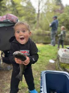 Erin Hawkinson / WDFW
A young child holds his first trout while smiling big for the camera.