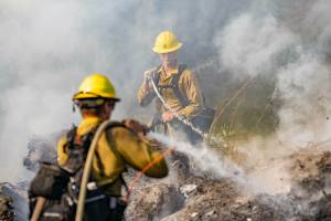KODY CHRISTEN
Wildland firefighters spray down a pile of burning brush as The Washington Department of Natural Resources assists Lewis County Fire in responding to a brush fire off of Beaver Creek Road in Boistfort on Thursday, Oct. 3.