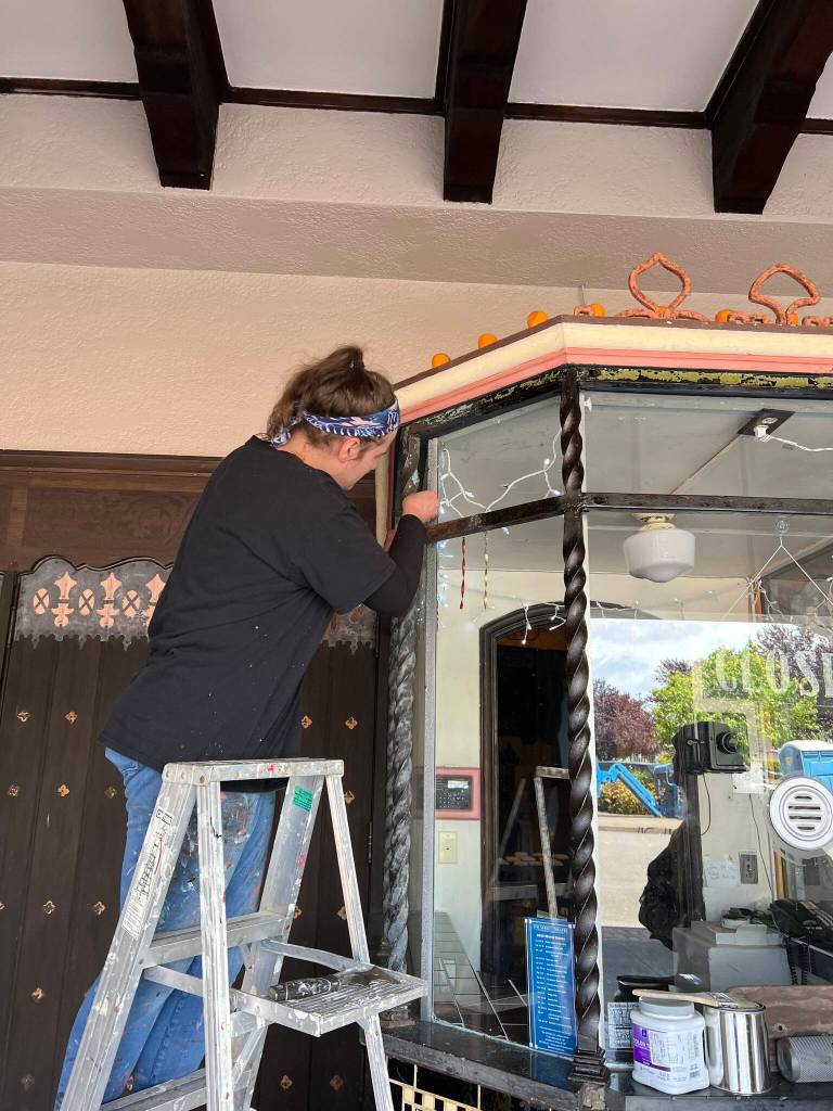 Katharine George from EverGreene Architectural Arts removes the rust, and refinishes and applies a protective coating and paint to the wrought iron posts in the ticket booth.
