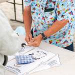 An experienced kite maker helps people build their own kite at the Kite Making Table, at Westport Windriders Kite Festival.
