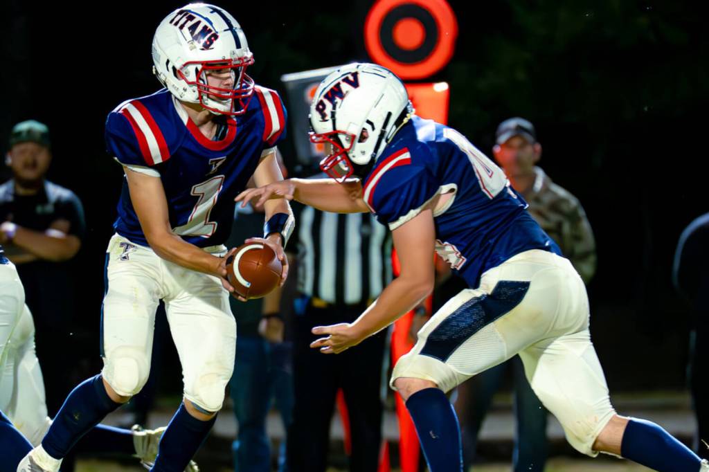 PHOTO BY MATT RUMBLES Pe Ell-Willapa Valley quarterback Brody Ritzman (left) hands the ball off to running back Spud Swogger during a win over Evergreen (Seattle) last week. The Titans host Blaine on Friday in Pe Ell.