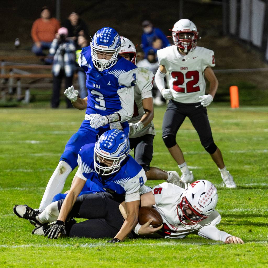 PHOTO BY MIKE ROBERTS Elma defenders Colt Landstrom (9) and Isaac McGaffey (3) pursue Kings quarterback Trey Dennison during the Eagles 46-0 loss on Friday at Elma High School.