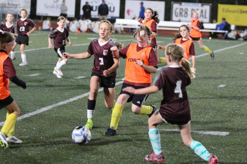 RYAN SPARKS | THE DAILY WORLD Players from Montesano Youth Soccers Raptors (orange) and Goats compete in an exhibition match at halftime of the Montesano-Rochester game on Thursday at Jack Rottle Field in Montesano.