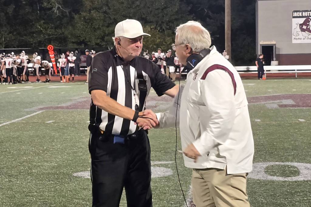 RYAN SPARKS | THE DAILY WORLD Montesano head coach Terry Jensen (right) shakes hands with referee Terry Simmons during a halftime ceremony honoring Simmons 50-plus year career on Friday at Montesano High School.