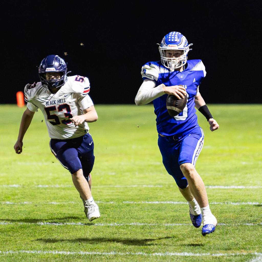 PHOTO BY MIKE ROBERTS Elma quarterback Isaac McGaffey (3) is pursued by Black Hills Cole Creekpaum during the Eagles 34-28 overtime victory on Friday in Elma.