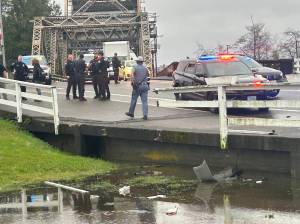 The Daily World photos
Police gather around where a woman crashed through a fence on the highway into Aberdeen on Monday.