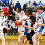 PHOTO BY MIKE ROBERTS Elmas Gavin Muir (left), Tyler Keith and Trey Yeager (right) defend Teninos Henry Czuleger during a 66-28 win over on Wednesday at Elma High School.