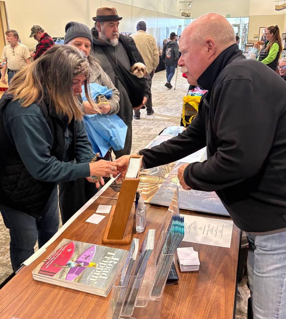 Jerry Knaak / The Daily World
John Shaw helps a festivalgoer at the Beachcombers and Glass Float Expo.