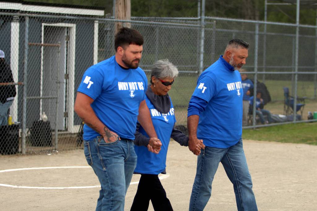 RYAN SPARKS | THE DAILY WORLD Mitchell Todds relatives (from left) Dalton Todd (son), Marlowe Todd (mother) and Jerry Todd (brother) walk to the pitching circle during a ceremony honoring the former Elma softball coach who dies in a vehicle accident on May 3.