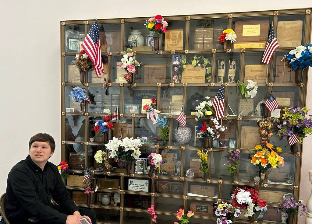 Submitted photo
Johnathan Bullard, an Aberdeen High School student who sang the National Anthem, sits next to the decorated memorial cabinet in the mausoleum at Fern Hill Cemetery on Monday.