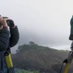 Stephani Gordon / OPB
Oregon State University field researcher Oceana Powers-Schmitz scans for whales next to the theodolite they use to map any whale blows, in Port Orford, Oregon.