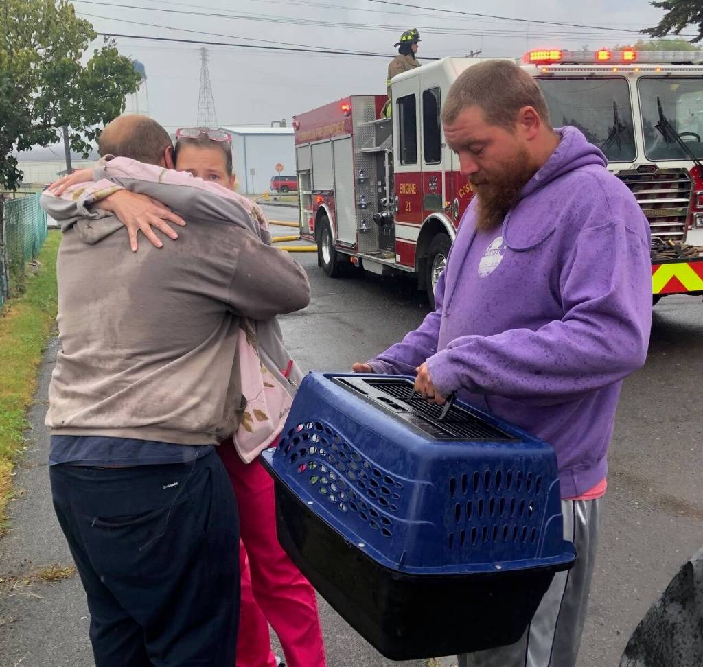 Michael Wagar / The Daily World
Family members are distraught, thinking their puppy was trapped inside a burning home. The crates hold two cats that were rescued.