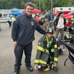 A member of the Montesano Fire Department helps a four-year-old try on the firefighter gear.