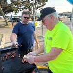 Ocean Shores City Administrator Scott Andersen and a community watch volunteer man the grill. (Jerry Knaak / The Daily World)