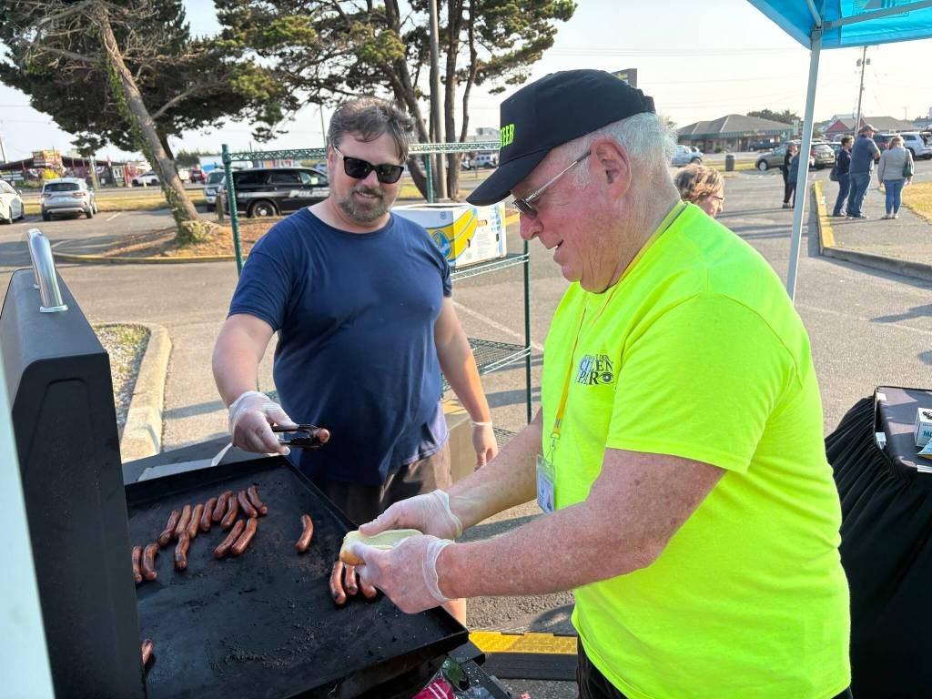 Ocean Shores City Administrator Scott Andersen and a community watch volunteer man the grill. (Jerry Knaak / The Daily World)